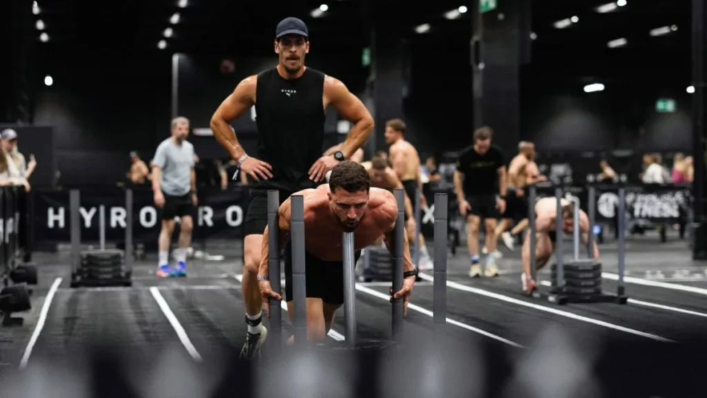 Atleta compitiendo en una prueba de alta intensidad Hyrox bajo estricta supervisión física.