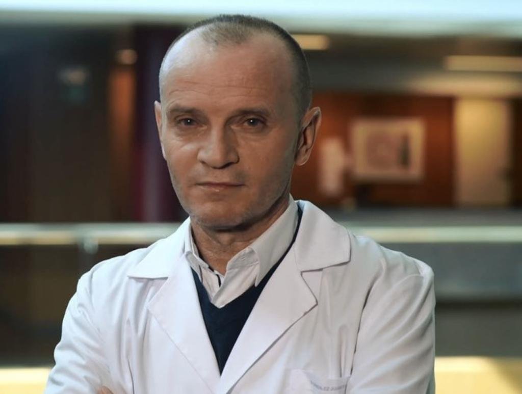 Médico evaluando la presión arterial a un paciente con un esfigmomanómetro aneroide y estetoscopio en consulta clínica.