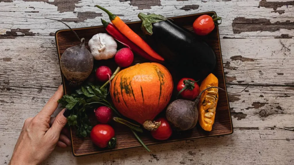 Variedad de verduras frescas de temporada incluyendo auyama, brócoli, zanahorias y hojas verdes dispuestas en una mesa clínica de nutrición
